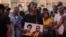 A man reacts as he holds an image of Paulo Guambe,left, and Elvino Dias, both associated with Mozambique's opposition party PODEMOS, during a vigil the day after they were shot dead in Maputo, Mozambique, Oct. 19, 2024.