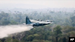 In this photo released by Brazil Ministry of Defense, a C-130 Hercules aircraft dumps water to fight fires burning in the Amazon rainforest, in Brazil, Aug, 24, 2019.