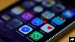 FILE - A WhatsApp icon (bottom, center) is seen on an iPhone.