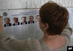 A polling station official hangs a list of candidates for the 2018 Russian presidential election, during preparations at a polling station in Simferopol, Crimea, March 17, 2018.
