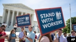 People gather at the Supreme Court awaiting a decision in an Illinois union dues case, Janus vs. AFSCME, in Washington, June 25, 2018. The Supreme Court says government workers can't be forced to contribute to labor unions that represent them in collective bargaining, dealing a serious financial blow to organized labor.
