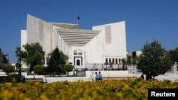 Police officers walk past the Supreme Court of Pakistan building, in Islamabad April 6, 2022, where a petition hearing to dissolve parliament by country's Prime Minister is taking place.