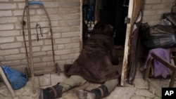 A dog stands next to the body of an elderly woman killed at the entrance of her house in Bucha, outskirts of Kyiv, Ukraine, April 5, 2022.