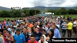 FILE - People cross the Colombian-Venezuelan border over the Simon Bolivar international bridge in Cucuta, June 10, 2019.