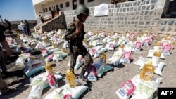 FILE - A Yemeni soldier, loyal to the Shi'ite Houthi movement, walks next to humanitarian aid supplies in a camp on the outskirts of the capital Sanaa, Yemen, March 16, 2017. 