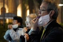 People with masks, blow whistles to representing whistleblower during a vigil for Chinese doctor Li Wenliang, in Hong Kong, Feb. 7, 2020.