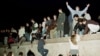 FILE - East German citizens climb the Berlin wall at the Brandenburg Gate as they celebrate the opening of the East German border.