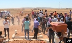 In this image made from video, mourners carry a coffin during the burial of Rehan Kurdi and her sons Alan, 3, and Galip, 5, after they drowned during a desperate voyage from Turkey to Greece, in their hometown of Kobani, the Syrian Kurdish region they fl