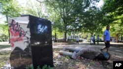 An unidentified man walks past a toppled statue of Charles Linn, a city founder who was in the Confederate Navy, in Birmingham, Ala., on Monday, June 1, 2020, following a night of unrest.