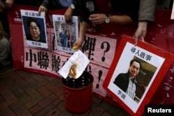 FILE - A pro-democracy activist burns a letter next to pictures of missing staff members of a publishing house and bookstore, including Gui Minhai, owner of Mighty Current, outside the Chinese liaison office in Hong Kong, Jan. 3, 2016.