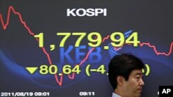 A currency trader passes by a screen showing the falling Korea Composite Stock Price Index (KOSPI) at the foreign exchange dealing room of the Korea Exchange Bank headquarters in Seoul, August 19, 2011