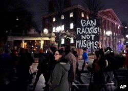FILE - Several hundred people march past the gates of Harvard Yard at Harvard University while protesting the travel ban in Cambridge, Mass., March 7, 2017.