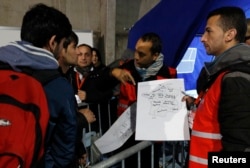 FILE - Migrants look at a map of France at a processing center to be registered on the second day of their evacuation and transfer to reception centers in France, during the dismantlement of the camp called "the Jungle" in Calais, France, Oct. 25, 2016.