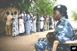 A police officer watches as women queue to vote during the recent referendum on South Sudan's independence. (April 2011)