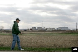 FILE - A man walks past a Marquis Energy LLC ethanol plant near Hennepin, Ill., April 4, 2007.