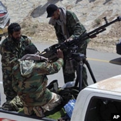Libyan rebels maintain a heavy machine gun mounted on top of a pickup truck during an exchange of fire with pro Gadhafi forces, outside the eastern town of Brega, Mar 31 2011