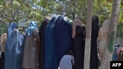 Internally displaced Afghan women, who fled from the northern province due to battle between Taliban and Afghan forces, gather to receive free food being distributed at Shahr-e-Naw Park in Kabul on Aug. 13, 2021. 