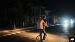 Un hombre pedalea cargando a una niña durante un corte de energía programado en Bauta, Cuba, el lunes 18 de marzo de 2024. La isla enfrenta una crisis energética, con oleadas de apagones que empeoraron en las últimas semanas. AP