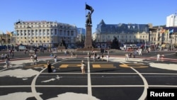 People walk over a tarmac with the Asia-Pacific Economic Cooperation (APEC) logo printed on it, in a central square of Vladivostok, Russia, September 6, 2012.