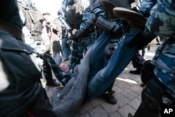 A detained woman looks out of a police bus in downtown Moscow, Russia, March 26, 2017. Russia's leading opposition figure Alexei Navalny and his supporters aim to hold anti-corruption demonstrations throughout Russia.