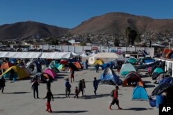 FILE - Migrants walk inside a former concert venue serving as a shelter in Tijuana, Mexico, Dec. 3, 2018.
