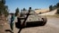 FILE - A young man walks past a destroyed tank near Debre Tabor, Ethiopia, Dec. 6, 2021.