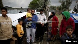 Syrian refugee Bashar Wakaa (3rd L) and his family stand in front of their tents at a makeshift camp for refugees and migrants next to the Moria camp on the island of Lesbos, Greece, Nov. 30, 2017.