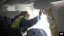 In this photo released by the National Transportation Safety Board, NTSB Investigator-in-Charge John Lovell examines the fuselage plug area of Alaska Airlines Flight 1282 on Jan. 7, 2024, in Portland, Ore. 