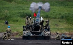 FILE - Japanese Ground Self-Defense Force soldiers fire a self-propelled howitzer during annual exercises near Mount Fuji at Higashifuji training field in Gotemba, west of Tokyo.
