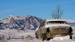Snow covers the burned remains of a car after wildfires ravaged the area Sunday, Jan. 2, 2022, in Superior, Colo.