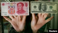 FILE - An exchange store staff shows a Chinese RMB$100 banknote (L) and a US$100 banknote in Hong Kong, May 16, 2006.