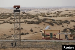 An Egyptian policeman gestures from an observation tower is seen from the Israeli side of the border with Egypt's Sinai peninsula, in Israel's Negev Desert Feb. 10, 2016.
