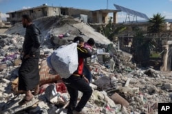 Warga mencari korban di antara puing-puing bangunan yang runtuh tempat bayi perempuan yang baru lahir ditemukan di Kota Jinderis, Aleppo, Suriah, Selasa, 7 Februari 2023. (Foto: AP)