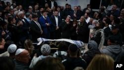 Mourners gather around the bodies of Israeli couple Eli Mizrahi and his wife, Natalie, victims of a shooting attack Friday in east Jerusalem, during their funeral at the cemetery in Beit Shemesh, Israel, Jan. 29, 2023. 