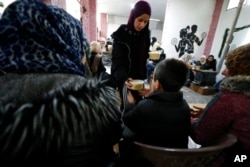 A volunteer distributes meals following a devastating earthquake, in Latakia, Syria, Feb. 10, 2023. The 7.8 magnitude quake that hit Turkey and Syria has displaced millions in war-torn Syria.