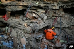 Seorang petugas penyelamat Turki memeriksa bangunan yang runtuh di Adiyaman, Turki selatan, 11 Februari 2023. (Foto: AP)