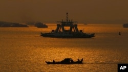 FILE - Cambodian fishermen on a motorized boat go fishing in the Mekong River in Phnom Penh, Cambodia, Feb. 2, 2021.