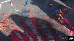 A representation of the U.S flag is set on fire by demonstrators during the annual rally commemorating Iran's 1979 Islamic Revolution, in Tehran, Iran, Feb. 11, 2023.