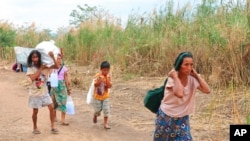 FILE - Displaced people from Myanmar carry donated lunch boxes to their tents along the Thai side of the Moei River in Mae Sot, Thailand on Feb. 5, 2022.