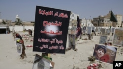 FILE- Religious flags, photographs and tributes to 21 victims of a suicide bombing, claimed by the Islamic State group, of a Shi'ite mosque are seen attached to their graves at a cemetery in Qudeeh, Saudi Arabia, May 30, 2015.