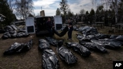 Cemetery workers unload bodies of killed civilians from a van in a cemetery in Bucha, on the outskirts of Kyiv, Ukraine, April 7, 2022.