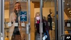 FILE - A shopper wearing a face mask to curb the spread of coronavirus walks out of a Marks and Spencer store on Oxford Street, in London, Jan. 27, 2022.