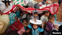 Syrian Kurdish refugees cover themselves from rain after crossing into Turkey from the Syrian border town Kobani, near the southeastern Turkish town of Suruc, Sanliurfa province, Oct. 2, 2014.
