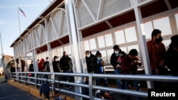 FILE - Migrants expelled from the U.S. and sent back to Mexico under Title 42 walk towards Mexico at the Paso del Norte International border bridge, in Ciudad Juarez, Mexico, April 1, 2022.