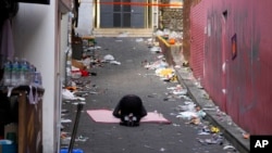 A man bows in the middle of the scene of a deadly accident following Saturday night's Halloween festivities in Seoul, South Korea, Monday, Oct. 31, 2022.