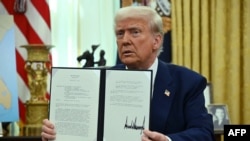 US President Donald Trump displays his signature on an Executive Order on reciprocal tariffs in the Oval Office of the White House in Washington, DC, on February 13, 2025.
