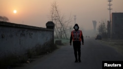 Artist Liu Bolin wearing a vest with 24 mobile phones walks in smog as he live broadcasts air pollution in the city on the fourth day after a red alert was issued for heavy air pollution in Beijing, China, Dec. 19, 2016. 