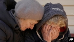 A neighbor comforts Natalya, whose husband and nephew were killed by Russian forces, as she cries in her garden in Bucha, Ukraine, April 4, 2022.