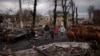 FILE - A family walks amid destroyed Russian tanks in Bucha, on the outskirts of Kyiv, Ukraine, April 6, 2022.