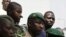 Lieutenant Amadou Konare, centre, spokesman for coup leader Amadou Haya Sanogo, unseen, is surrounded by security as he arrives to address supporters, as thousands rallied in a show of support for the recent military coup, in Bamako, Mali, March 28, 2012.